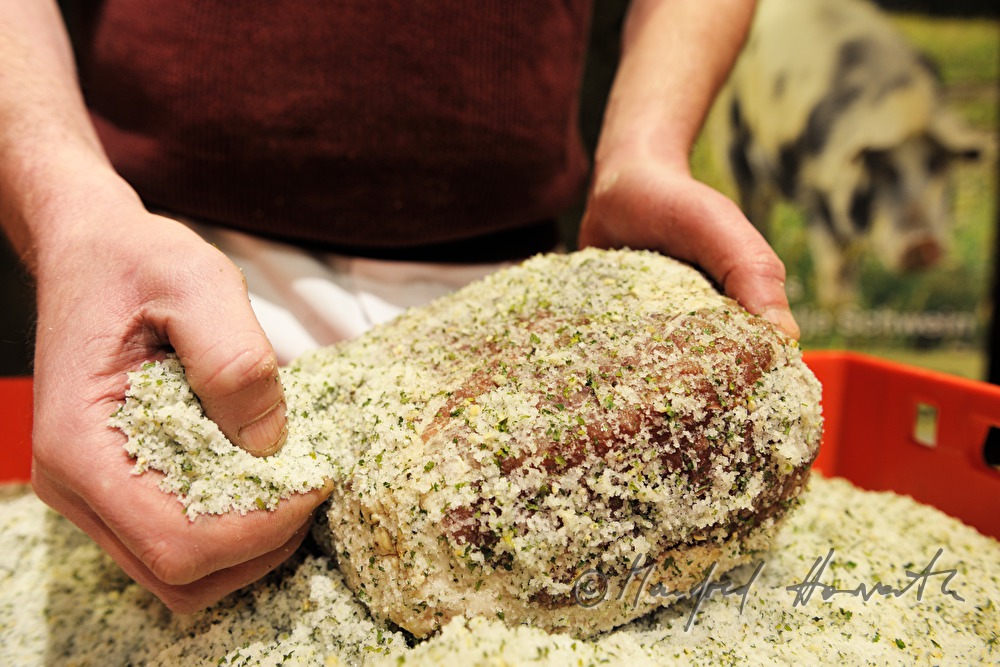 Fleischermeister salzt Porcella Rohschinken ein
