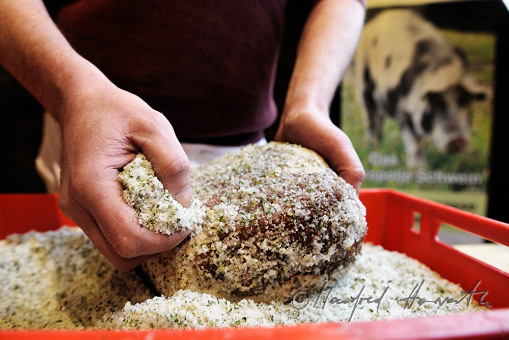 Fleischermeister salzt Porcella Rohschinken ein