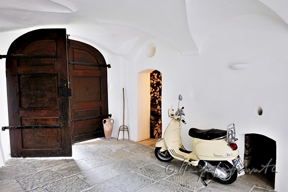 Einfahrt mit Motorroller und Holzlager
