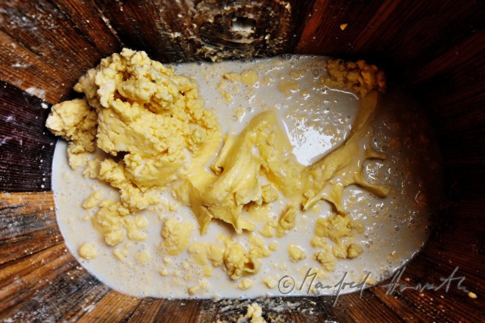 Senner rührt Butter im Butterfass