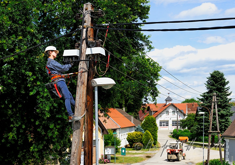 Elektromonteurin klettert auf einen Strommast