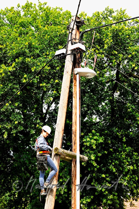 Elektromonteurin klettert auf einen Strommast