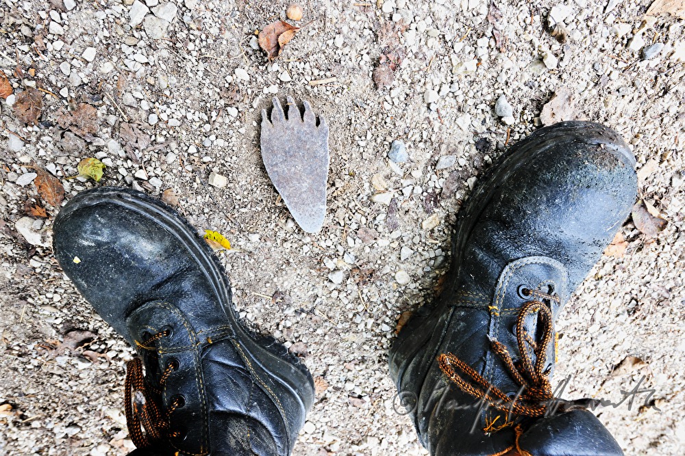 Metall-Fussabdruck eines Ütscherbären und Schuhe eines Wanderers