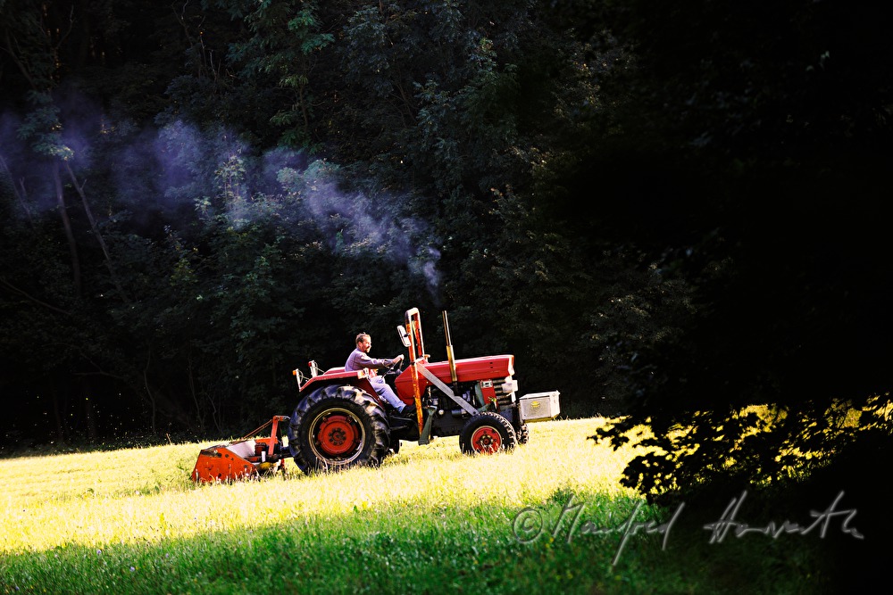 Bauer mäht die Wiese mit Traktor-Mähbalken