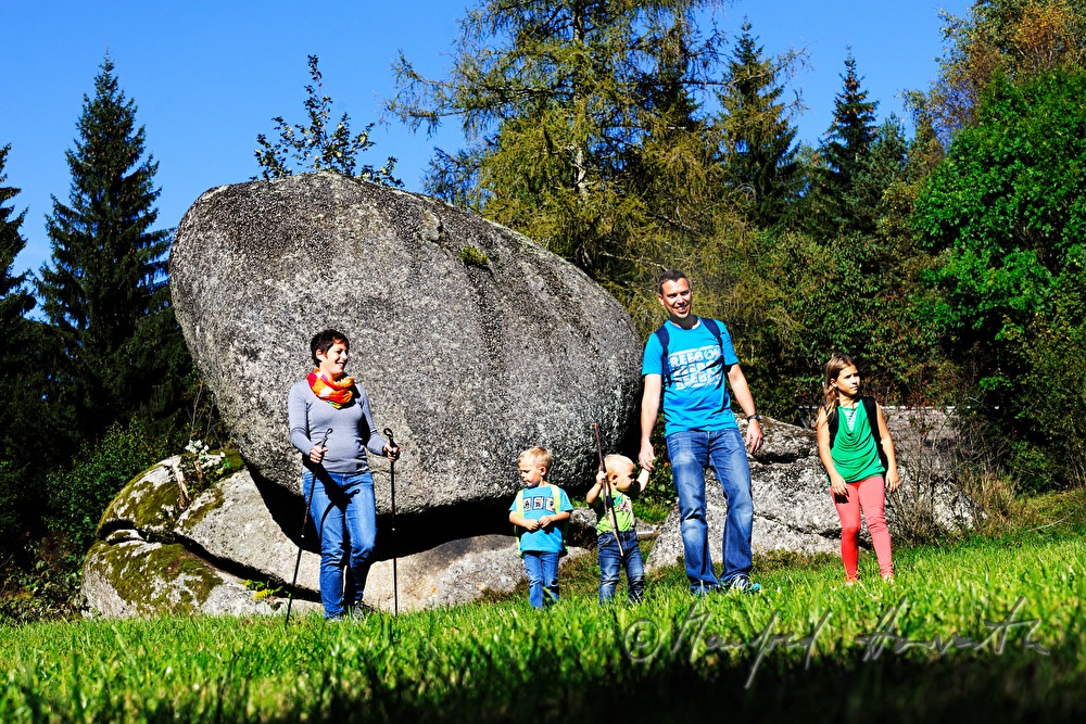 Familie wandert am Granitblock vorbei