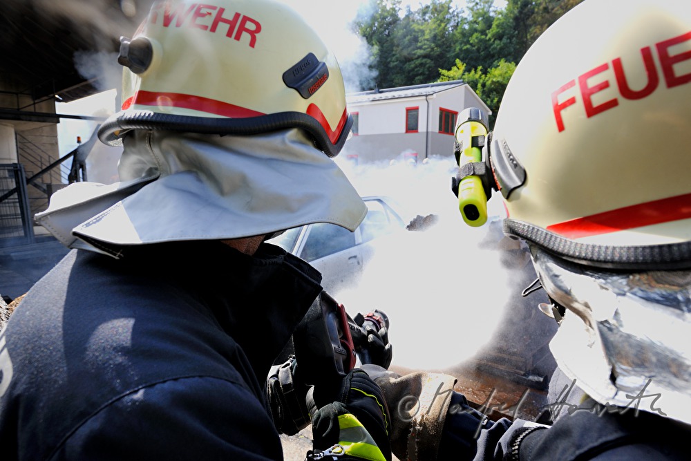 Feuerwehr-Schüler löschen ein brennendes Auto bei einer Übung