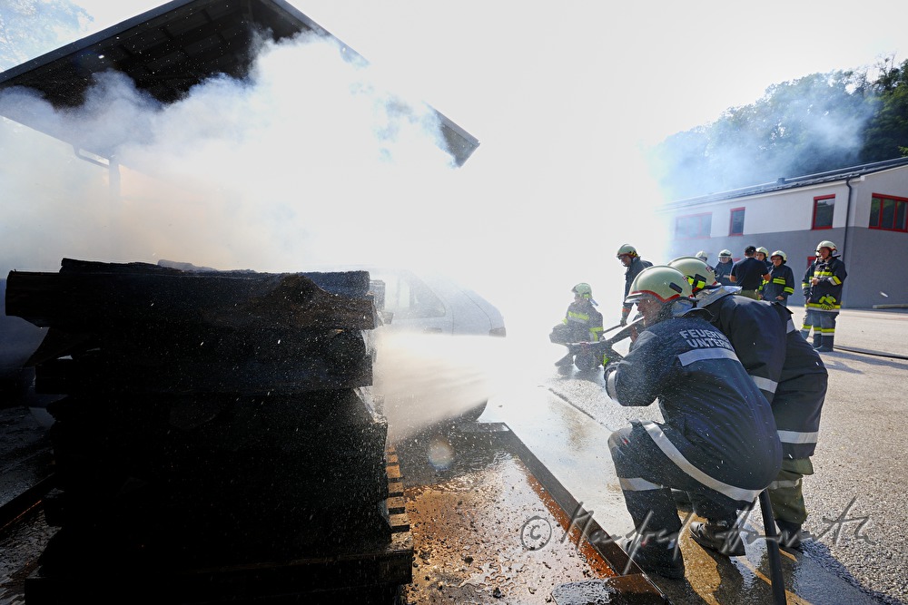 Feuerwehr-Schüler löschen ein brennendes Auto bei einer Übung