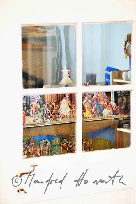 Blick durchs Fenster in den nächsten Raum mit Weihnachtskrippen