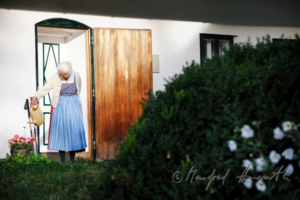 Frau Fuchs gießt die Blumen vor ihrem Bauernhaus