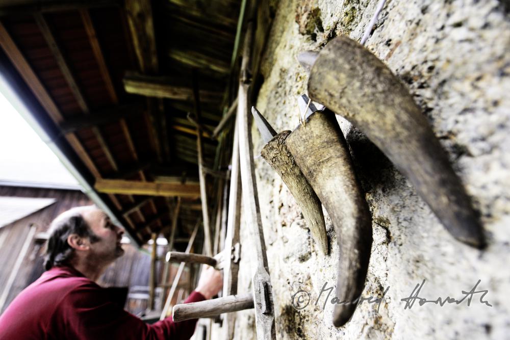 Köcher für Sensen-Wetzsteine aus Horn hängen an der Scheunenmauer