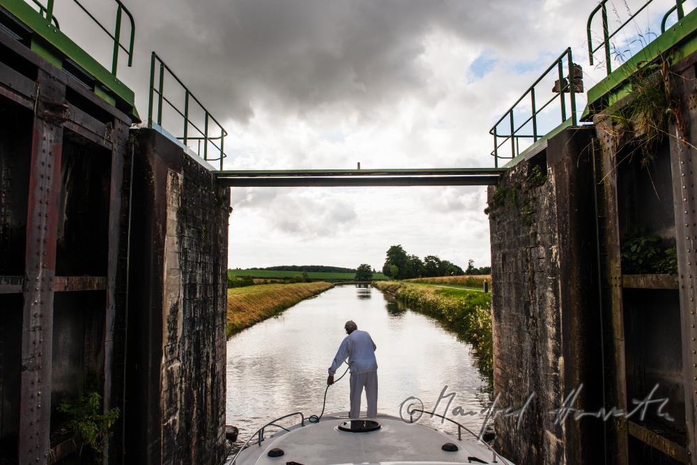 Hausboot kommt aus der Schleuse der Ortschaft Rully