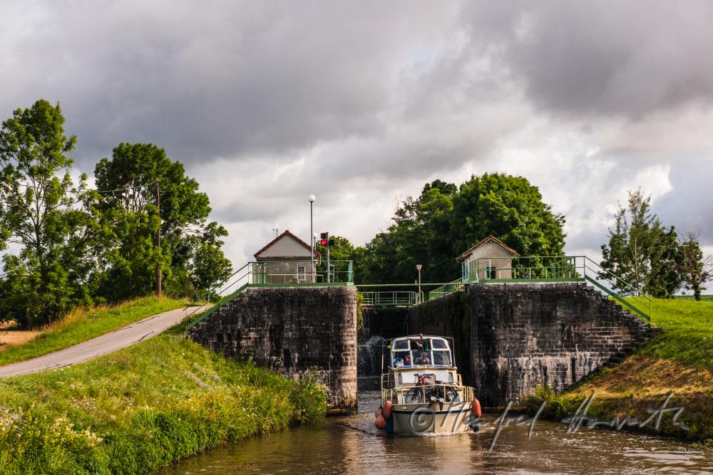 Hausboot kommt aus der Schleuse der Ortschaft Rully