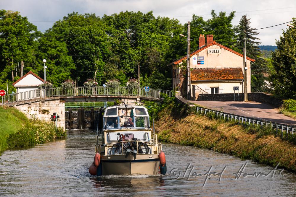 Hausboot kommt aus der Schleuse der Ortschaft Rully