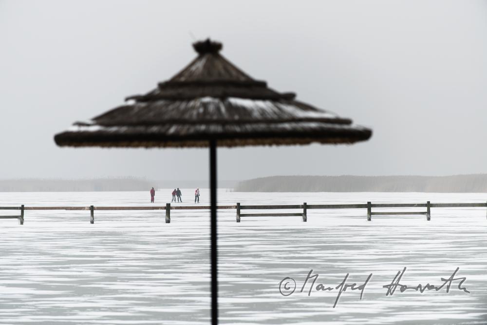 Schilf-Sonnenschirm und Eisläufer auf dem See