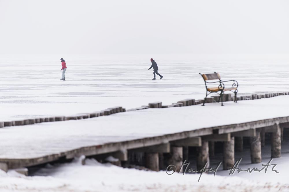 schneebedeckter Landungssteg und Sitzbänke