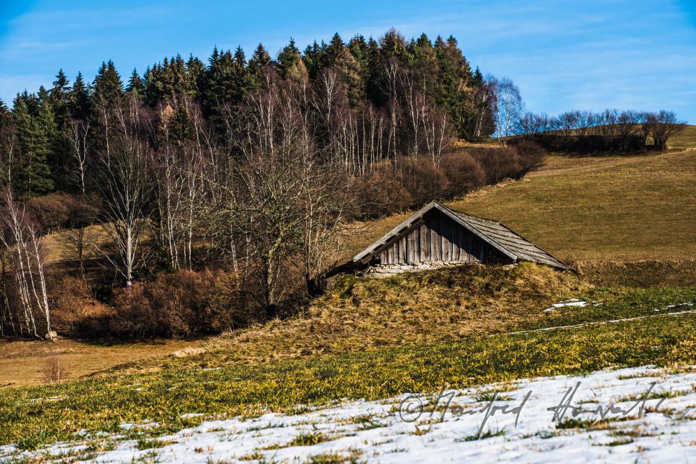 halb in der Erde liegender Erdäpfelkeller in einem Feld abseits des Bauernhauses