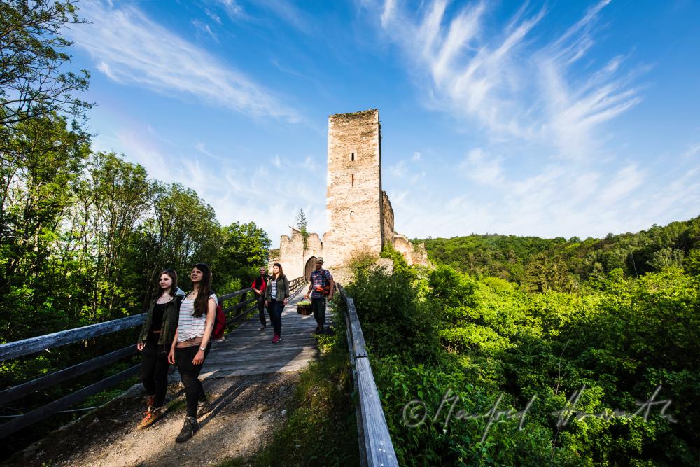 Burg Kaja und Wanderer auf der Holzbrücke
