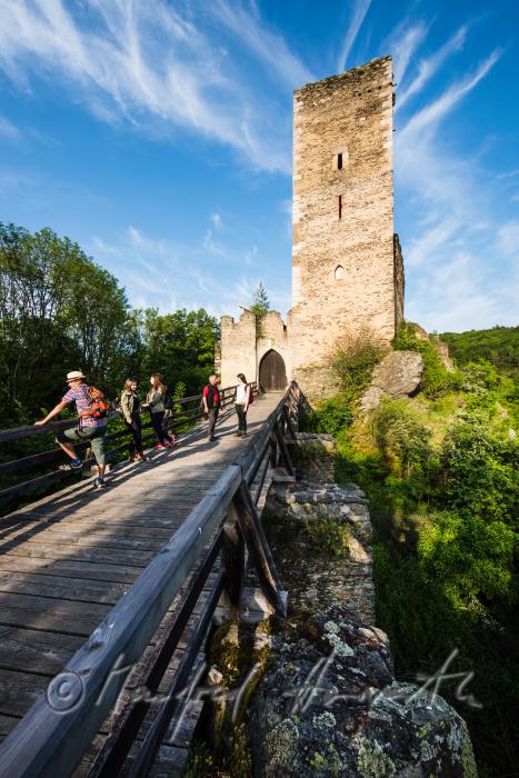 Burg Kaja und Wanderer auf der Holzbrücke