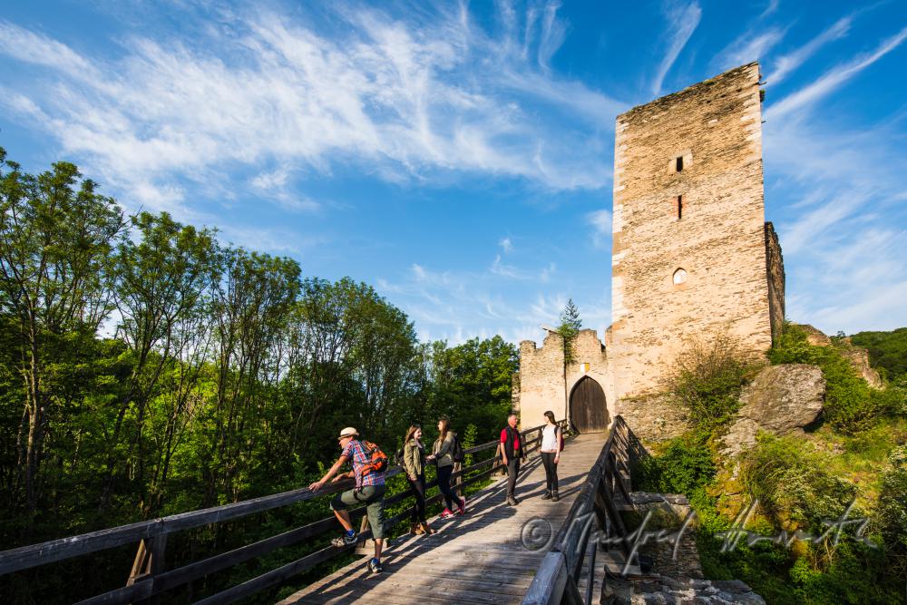 Burg Kaja und Wanderer auf der Holzbrücke